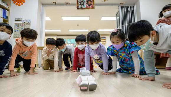 Un grupo de niños estudiantes hacen flexiones con un robot en Seúl.