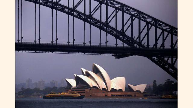 The sun illuminates The Sydney Opera House as a ferry sails past during a storm at Sydney Harbour in Australia; La ópera de Sidney con un ferry saliendo del puerto a finales de noviembre de 2016 (Australia).(foto:David Gray).