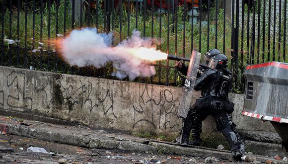 Un oficial de la policía antidisturbios lanza gases lacrimógenos a los manifestantes durante una protesta contra el gobierno en Cali, Colombia, el 10 de mayo de 2021. (Luis ROBAYO / AFP).