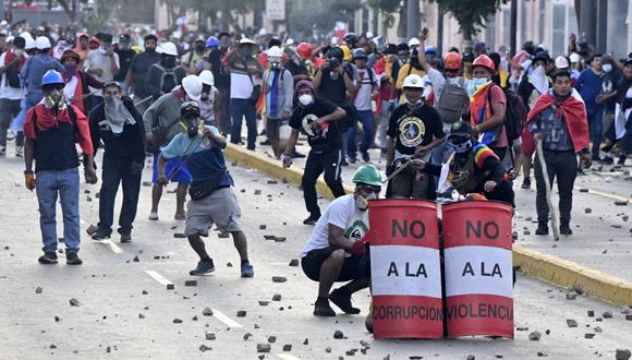 Manifestantes arrojan piedras a policías antidisturbios durante enfrentamientos dentro de una protesta en Lima el 24 de enero de 2023. (Foto de Ernesto Benavides / AFP)