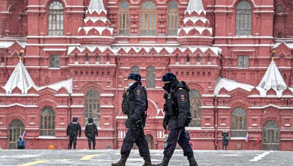 Dos policías con una máscara facial para protegerse contra la enfermedad del coronavirus covid-19 caminan por la Plaza Roja bajo la nieve cerca del Kremlin en Moscú el 8 de marzo de 2021.
(Foto referencial, Yuri KADOBNOV / AFP).