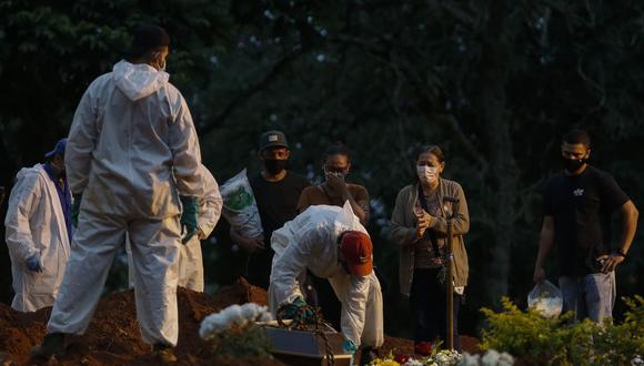La gente llora mientras un familiar es enterrado en el cementerio de Vila Formosa en Sao Paulo, Brasil, el 17 de abril de 2021. (Miguel SCHINCARIOL / AFP).