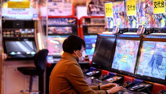 Un hombre con una máscara facial, en medio de las preocupaciones sobre la propagación del nuevo coronavirus COVID-19, juega un videojuego en un centro de juegos en el distrito de Akihabara de Tokio, el 8 de marzo de 2020. (Foto de Philip FONG / AFP).