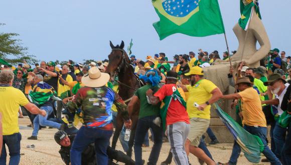 Un oficial de la Policía Militar se cae de su caballo durante los enfrentamientos con partidarios del expresidente brasileño Jair Bolsonaro luego de una invasión al Palacio Presidencial de Planalto en Brasilia el 8 de enero de 2023.