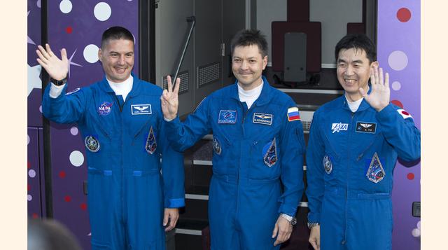Los astronautas Kjell Lindgren de EE.UU., Oleg Kononenko de Rusia y Kimiya Yui de Japón saludan a la prensa en tanto se alistan para abordar la nave Soyuz que los transportará a la Estación Espacial Internacional (ISS). El cohete partió desde el cosmódrom