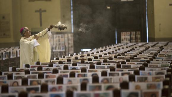 El arzobispo de Lima Carlos Castillo balancea un incensario los más de 4 mil retratos de víctimas del COVID-19 durante la misa de Corpus Christi en la Catedral de Lima, el pasado domingo 14 de junio. (Foto: Rodrigo Abd / AP)