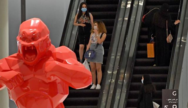 Las personas, que usan máscaras protectoras para combatir la propagación del coronavirus, caminan en el centro comercial de Dubai. (AFP / Karim SAHIB).