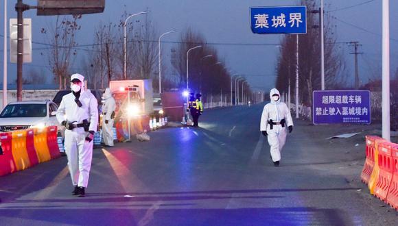 Agentes de policía y miembros del personal con trajes protectores inspeccionan vehículos en un puesto de control en las fronteras del distrito de Gaocheng, Shijiazhuang. (China Daily/REUTERS).