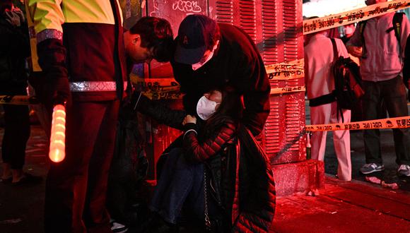 Una mujer es atendida mientras decenas de personas sufrían un paro cardíaco en el popular distrito de vida nocturna de Itaewon en Seúl el 30 de octubre de 2022. (Foto de Anthony WALLACE / AFP)