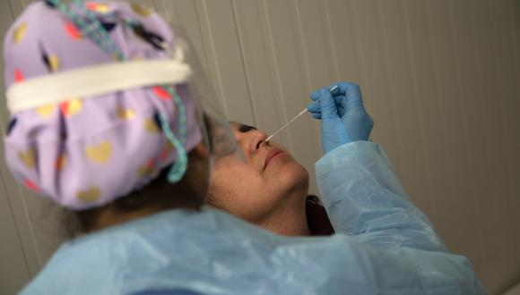 Un trabajador de la salud con equipo de protección recolecta un hisopo nasal para una prueba de PCR Covid-19 antes de un concierto de música en Santiago. (Foto: CLAUDIO REYES / AFP)