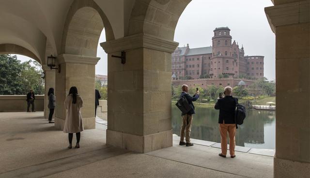 FOTO 1 | Miembros de los medios de comunicación visitan el campus de Huawei en Dongguan, China. El castillo marrón del otro lado del lago artificial está inspirado en el castillo de Heidelberg en Alemania, y albergará la unidad de investigación secreta de Huawei. (Foto: Bloomberg)