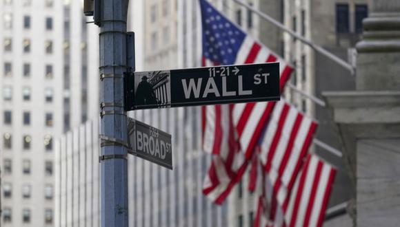 FILE - The Wall St. street sign is framed by the American flags flying outside the New York Stock exchange, Friday, Jan. 14, 2022, in the Financial District.   Stock prices have tumbled 10% since the S&P 500 set its record high early this year, hurt by worries about interest rates, inflation and conflict in Ukraine. But based on measures that Wall Street uses to gauge stocks, they look perhaps 15% cheaper.  (AP Photo/Mary Altaffer, File)