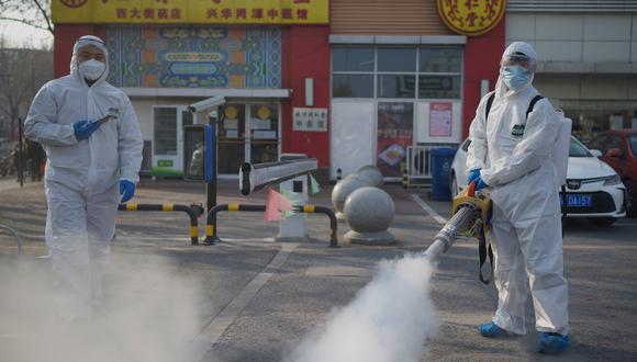 Trabajadores que usan trajes para materiales peligrosos desinfectan las instalaciones de un mercado en el distrito Daxing de Beijing el 21 de enero de 2021 (Foto: Noel Celis / AFP)
