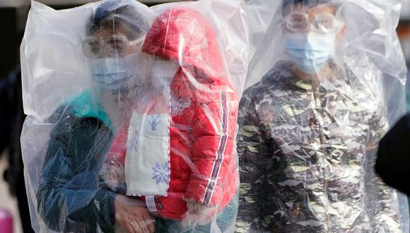 Un grupo de personas que usa máscaras y están cubiertas con bolsas de plástico caminan afuera de la estación de trenes de Shanghai, China, país afectado por el coronavirus. (REUTERS / Aly Song).
