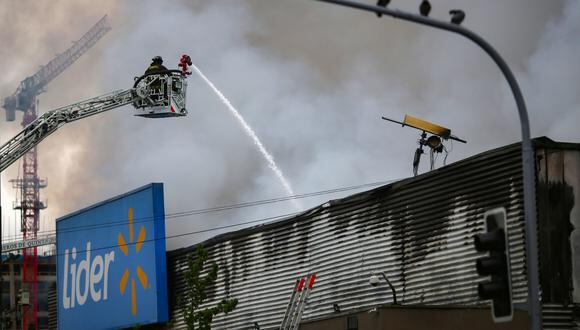 Bomberos apagan un incendio en el supermercado Líder. (Foto: AFP)