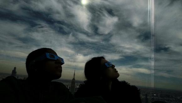 La gente mira hacia el cielo en la plataforma de observación 'Edge at Hudson Yards' durante un eclipse solar total en América del Norte, en la ciudad de Nueva York el 8 de abril de 2024. (Foto de Charly TRIBALLEAU / AFP)