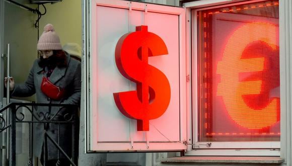 Una mujer sale de una oficina de cambio de divisas que muestra el signo del dólar estadounidense y el euro en San Petersburgo, Rusia, el 2 de marzo de 2022. Olga MALTSEVA AFP