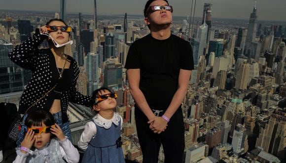 Las personas miran hacia el cielo en la plataforma de observación 'Edge at Hudson Yards' durante el eclipse solar en la ciudad de Nueva York. (Foto: Charly TRIBALLEAU / AFP)