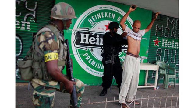 Kingston, Jamaica. Homicidios: 495. Población: 1.219.366. Tasa de homicidios: 40.59. En la imagen: Un soldado cachea a un hombre en un control militar en el vecindario de Tivoli Gardens en Kingston, Jamaica.