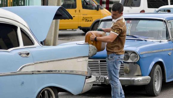 Corriendo con su bidón repleto de combustible, un cubano se apresura a llenar el depósito de su auto aparcado más lejos. “Solo dan 20 litros”, dice antes de regresar a la fila con la esperanza de conseguir más. (Foto referencial)