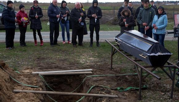 La gente se reúne junto a un ataúd con el cuerpo de Ruslan Nechyporenko, asesinado en medio de la invasión de Rusia, durante su funeral en la ciudad de Bucha. (REUTERS/Volodymyr Petrov)