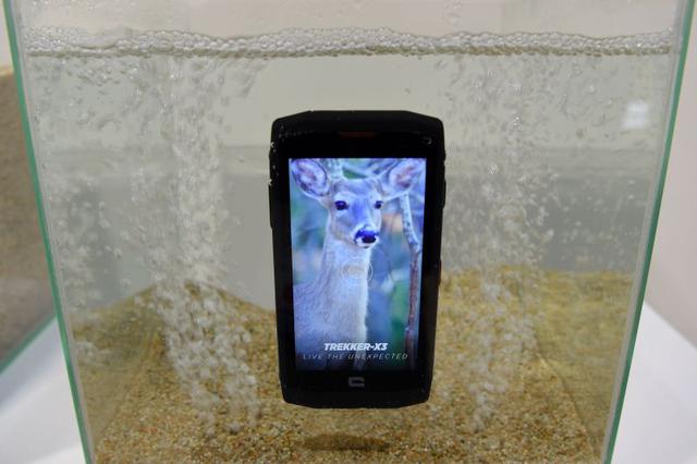 El smartphone Crosscall Trekker-X3 es exhibido en un recipiente lleno de agua y arena. (Foto: AFP)