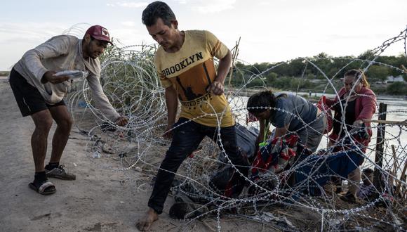 Migrantes de Venezuela trepan por alambre de púas después de cruzar el río Grande en la frontera entre Estados Unidos y México en Eagle Pass, Texas, el 24 de septiembre de 2023 (Foto: Andrew Caballero-Reynolds / AFP)