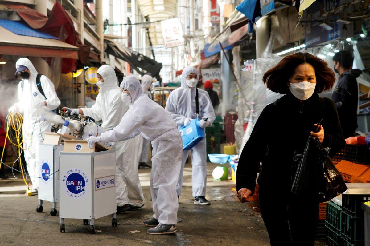Una mujer con mascarilla camina mientras se produce una fumigación en plena crisis por el coronavirus en Corea del Sur. (Foto: Reuters)