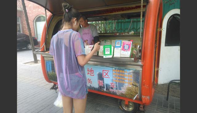 FOTO 1 | 1. Wechat y Alipay se han convertido en las principales plataformas para realizar operaciones de pago por la compra de productos y servicios en zonas urbanas de China. En la imagen, una joven de Beijing compra un bocadillo al paso.