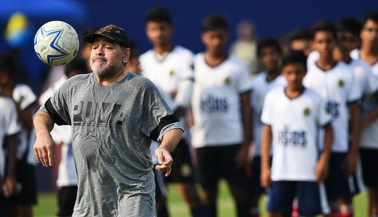 Argentine footballer Diego Maradona (L) plays the ball during a football workshop with school students in Barasat, around 35 Km north of Kolkata on December 12, 2017. Maradona is on a private visit to India. / AFP / Dibyangshu SARKAR