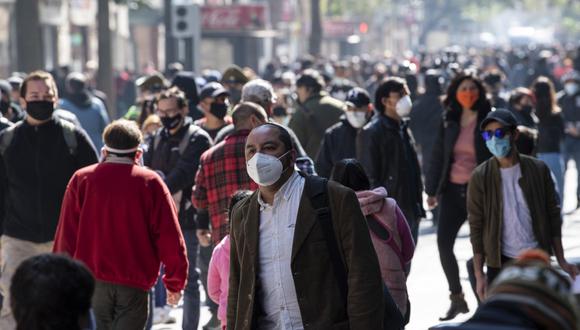 Un gran numero de transeuntes usan mascarillas mientras caminan por una calle en el centro de Santiago, luego de la flexibilización de las medidas de confinamiento ante la pandemia del COVID-19. (Photo by Martin BERNETTI / AFP)