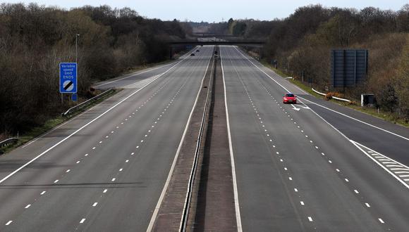 Un automóvil pasa por la autopista M3 casi desierta cerca de Fleet, al suroeste de Londres. El Reino Unido ha decretado confinamiento para frenar el brote de coronavirus. (AFP / Adrian DENNIS).