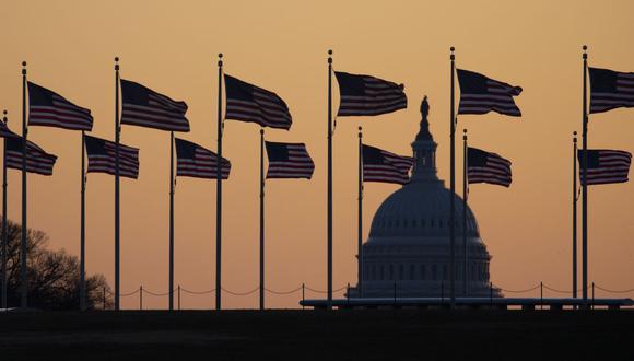 Las banderas estadounidenses soplan en el viento con el Capitolio de los Estados Unidos en el fondo al amanecer. (Foto: AP)