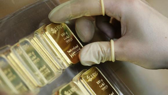 An employee wears gloves to hold a 100g gold bar, engraved with the logo and name of the swiss bank UBS, on April 6, 2009 at a plant of gold refiner and bar manufacturer Argor-Heraeus SA in Mendrisio, southern Switzerland. AFP PHOTO / Sebastian Derungs (Photo by SEBASTIAN DERUNGS / AFP)