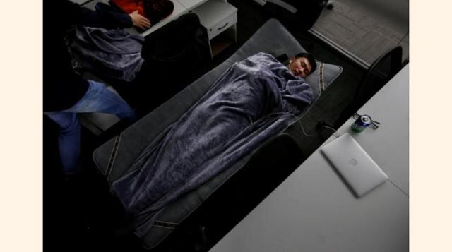 Han Liqun (al centro), gerente de Recursos Humanos de RenRen Credit Management Co., duerme en una cama plegable en su oficina después de terminar su trabajo durante la madrugada en Pekín, China. (Foto: Reuters)