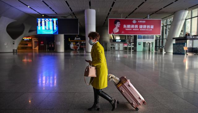 Una mujer con una máscara facial es vista en la estación de ferrocarril de Wuhan, provincia central de Hubei de China, el 28 de marzo de 2020. (AFP).