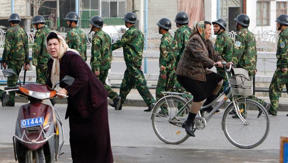 Mujeres uigures pasan al lado de las fuerzas de seguridad chinas mientras patrullan una calle en Yecheng, en la región de Xinjiang. La imagen es de abril del 2008. (Foto: Reuters)