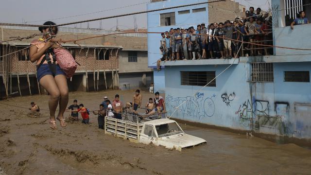 Una mujer se ve forzada a cruzar la calle por los aires debido a la inundación de las vías por el huaico. (Foto: AP)
