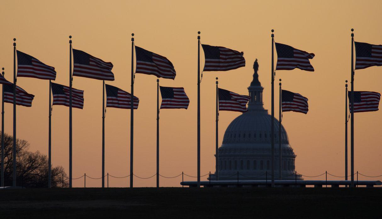 Las banderas estadounidenses soplan en el viento con el Capitolio de los Estados Unidos en el fondo al amanecer. (Foto: AP)
