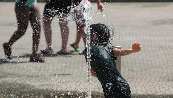 Un niño juega con agua para refrescarse este viernes en la ciudad española de Bilbao, al norte del país. EFE/Luis Tejido.