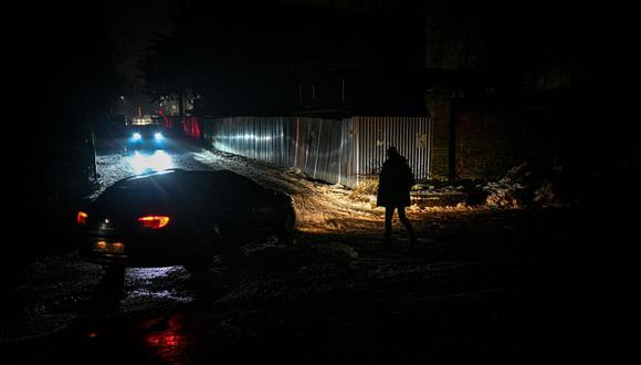 Un peatón camina por una calle oscura durante un apagón en Lviv el 16 de diciembre de 2022, después de que los ataques rusos atacaran la infraestructura eléctrica. (Foto de YURIY DYACHYSHYN / AFP)