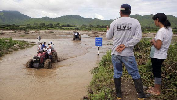 Personas que viven en el campo a las afueras del pueblo de Chiclayo, 770 kilómetros al norte de Lima, usan un tractor para cruzar las crecientes aguas del río Zana el 19 de marzo de 2017. (Foto de Julio Reano / AFP)