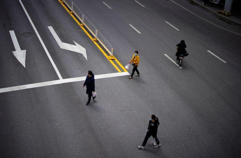 Personas con mascarillas cruzan una carretera después de que el confinamiento contra el coronavirus (COVID-19) se levantó en Wuhan, provincia de Hubei, China, el 14 de abril, 2020. REUTERS/Aly Song