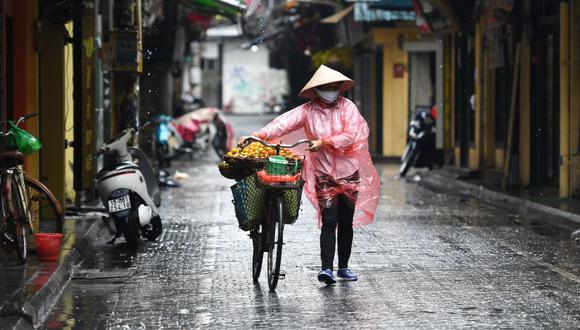 Una vendedora de frutas que usa una máscara facial camina por una calle en Hanoi, Vietnam. (Foto: Nhac NGUYEN / AFP).