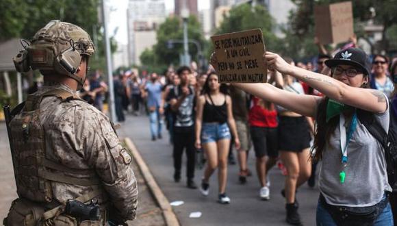 Manifestantes chilenos exponen un cartel delante de un militar, durante las protestas contra el gobierno del presidente Sebastián Pinera. (NURPHOTO).