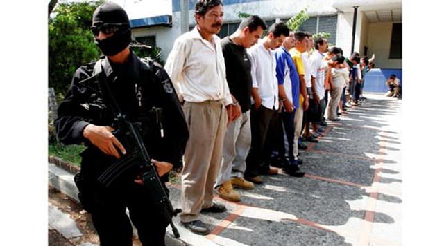 San Salvador, El Salvador. Homicidios: 1.067. Población: 1.743.315. Tasa de homicidios: 61.21. En la imagen: Un oficial de policía monta guardia mientras los medios exponen a supuestos miembros de una banda criminal en San Salvador.