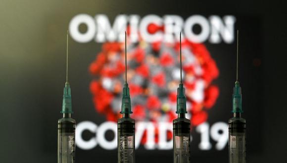 Una imagen de ilustración tomada en Londres el 2 de diciembre de 2021 muestra cuatro jeringas y una pantalla que muestra la palabra 'Omicron', el nombre de la nueva variante del covid 19 y una ilustración del virus. (Foto: Justin Tallis / AFP)
