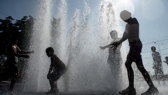 Niños juegan en una fuente durante un caluroso día de verano en la plaza principal de Santiago. (Foto: MARTIN BERNETTI / AFP)