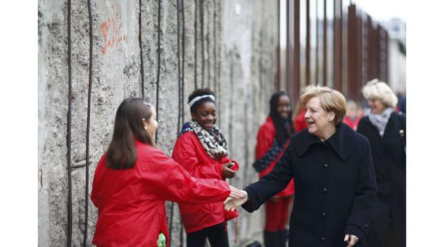 La canciller alemana, Angela Merkel, saluda a los niños que simbolizan a los mauerspechte, personas que derribaron a punta de martillo, el muro de Berlín. (Foto: Reuters)