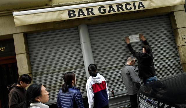 La gente observa cómo un hombre pone un aviso informando a los clientes que el bar está cerrando para prevenir el coronavirus, en Pamplona, ​​norte de España. (Foto: AP)